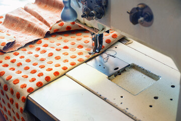 Industrial sewing machine processing an upholstery fabric for home decoration in a craft workshop,...