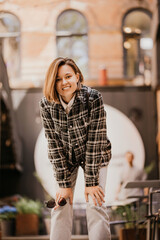 Cheerful and beautiful brunette in a plaid shirt on a walk. 