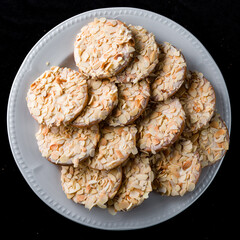 Sweet shortcrust pastry cookies with cream and almonds on a white plate.