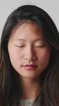 Close up, young woman opens her eyes looking at camera, isolated over white background in studio
