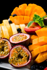 Healthy food fruit and berry plate with mango, pineapple, passion fruit, strawberry, blueberry and mint.