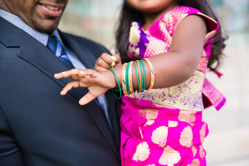 Fototapeta premium close up of dad admiring his daughter's traditional indian bracelets while wearing a sari