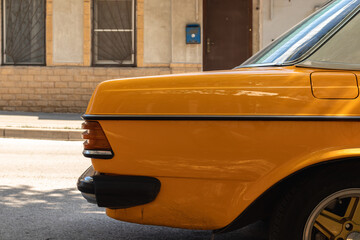 Cropped photo of a bright yellow vintage car . Side view image