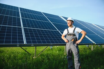 Side view of male worker installing solar modules and support structures of photovoltaic solar...