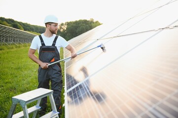 A handyman cleaning solar panels form dust and dirt.