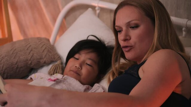 Mom reads a book to her daughter at bedtime