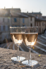 French rose dry wine from Provence in two glasses in sunny day with view on old streets of Arles town.