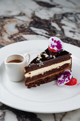 Portion of chocolate cake with vanilla cream, strawberries and caramel sauce.