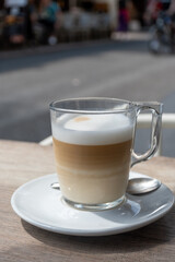 White cup of coffee latte served in outdoor cafe in France