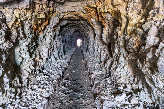 Natural light illuminated a pedestrian tunnel blasted through Red argillite and quartzite rock, Ptarmigan Tunnel, Glacier National Park, Montana