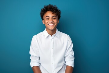 smiling young man in white shirt against blue background,