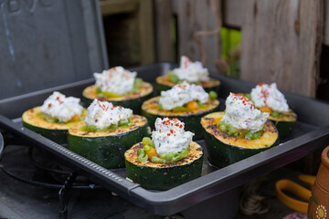 Zucchini slices stuffed with peas and carrots topped with cream cheese on a baking sheet.