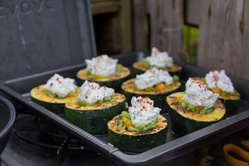 Zucchini slices stuffed with peas and carrots topped with cream cheese on a baking sheet.