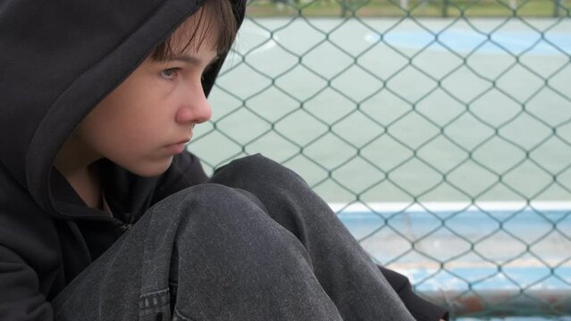 Teen trapped in sadness. A young girl trapped in sadness because of loneliness on fenced school yard.