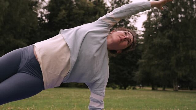 Pregnant woman doing yoga exercise outdoors