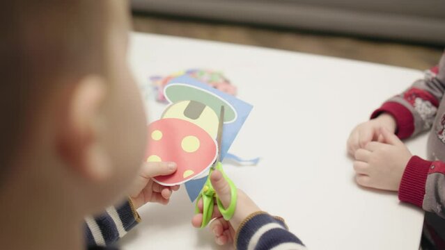 child learning to use scissors preschooler boy holding scissors in hand learning cut paper picture of colorful mushroom or turtle. baby hands, developing fine motor skills, kid has home education