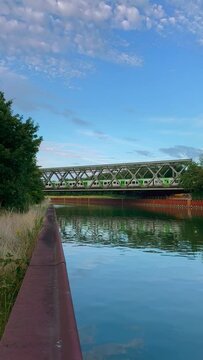 Train crossing a river bridge in sunny Sumer day, vertical video background