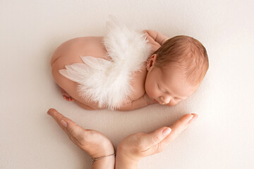 A cute newborn boy in the first days of life sleeps naked against a background of white fabric. New...