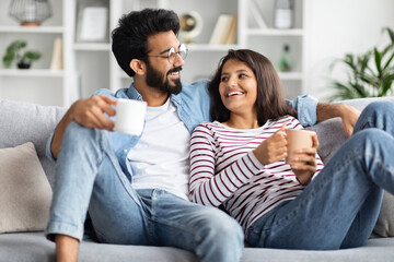 Loving beautiful eastern couple drinking coffee at home