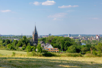 Fototapeta premium Summer landscape, The terrain of hilly countryside green grass meadow and farmland in Zuid-Limburg, Houses and church on hillside under blue sky, Maastricht is a capital city of Limburg, Netherlands.
