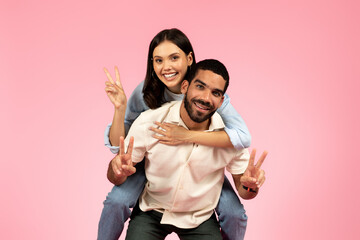 Happy cute loving couple having fun on pink background