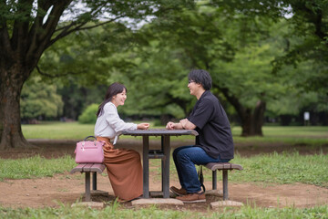 公園でベンチに座って話をするカップル