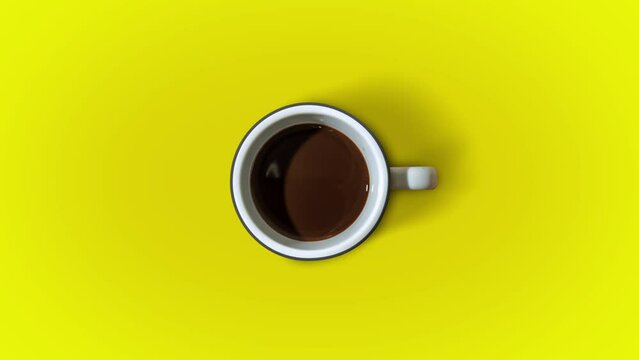 Coffee fills the cup in stop motion on a yellow background