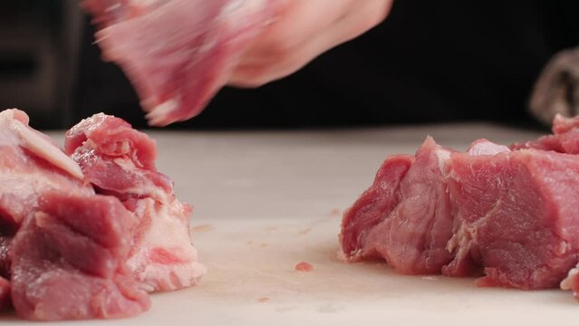 Chef Butcher cutting pork meat with knife on kitchen, cooking Mexican traditional food. Man cut big beef piece for barbecue bbq.
