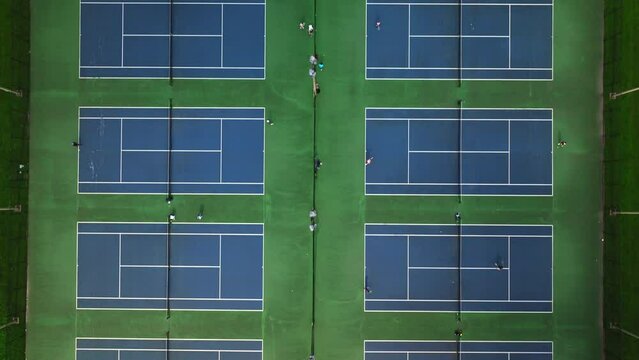 Aerial shot of blue tennis courts and people playing tennis