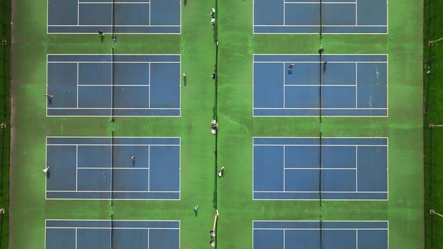 Aerial shot of blue tennis courts and people playing tennis