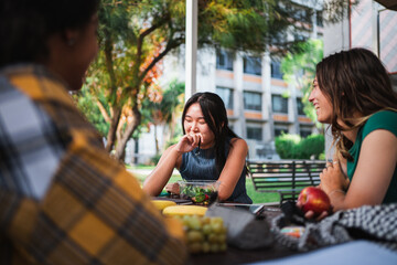 Laughing student girls having a snack at the college campus while they are resting from studying