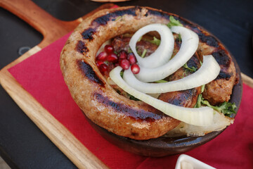 Top view, curl of Kupati,  Georgian spicy sausage with distinct flavor, on top with onion and barberry.