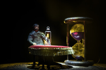 Time concept. Silhouette of a man standing between hourglasses with smoke and lights on a dark background.