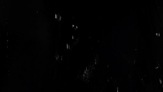 Water splashes on a window closeup with a black background 