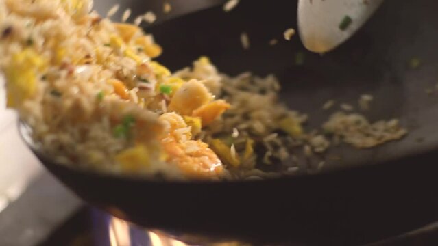 Stir frying and frying seafood fried rice in wok, peruvian style, with high heat, Slow motion