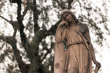 religious statue figure of melancholic woman thinking in an outdoor cemetery