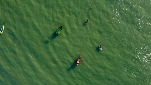 Rising top down aerial footage showing typical small fishing boats floating in the ocean. Guarapari, Espirito Santo, Brazil.