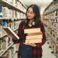 Young woman student picking literature for education, checking information in books while other...