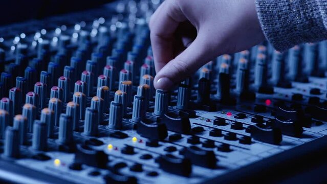 hand moving different volume and equalization controls on professional mixing console