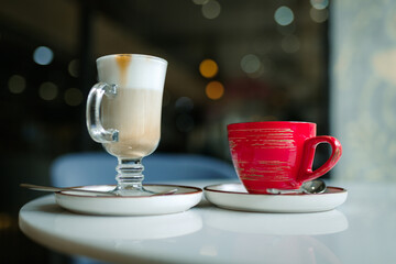 Two cups of coffee stand on a table in a coffee shop, latte and cappuccino, coffee date.