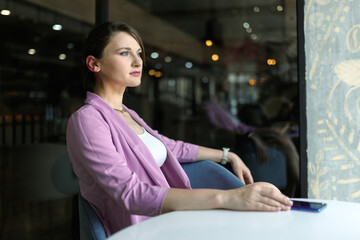 Young caucasian woman sitting in restaurant waiting for a man who is late for a date.