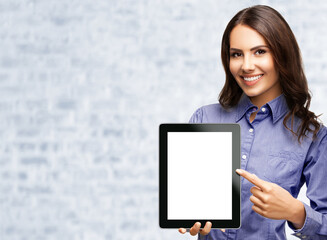 Image of smiling brunette businesswoman showing blank tablet pc monitor, with copy space area for...