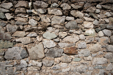 Old background of natural stones of different sizes bonded with cement mortar.