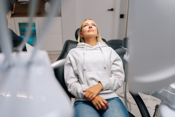 Portrait of worried thoughtful scared female patient lying in medical chair in dental office before treatment in clinic. Dentistry, stomatology phobia, fear. Concept of dentistry and teeth care.