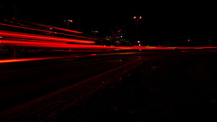 Lights of cars at night. Street line lights. Night highway city. Long exposure photograph night road. Colored bands of red light trails on the road. Background wallpaper defocused photo. 