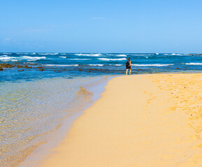 Fototapeta na wymiar Female Tourist Walking on The Sandy Shore of Poipu Beach., Koloa, Kauai, Hawaii, USA
