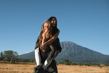A guy and a girl, of European appearance, have fun, enjoy life, hug each other in nature, against the backdrop of the Agung volcano, in Bali.