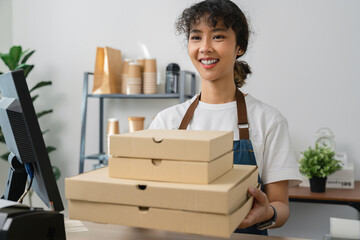 Fototapeta na wymiar Studio shot of Beautiful Asian woman cashier wears an apron and holding pizza boxes on restaurant counter.