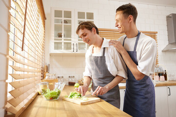 LGBT gay couple cooking vegetables together in the kitchen