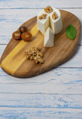 fresh cheese with walnuts, honey and cherry tomato on a wooden board with copy space